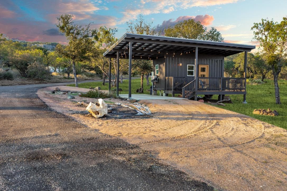 Groomsmen Lodge exterior with a wide covered porch and string lights facing the Hill Country at dusk
